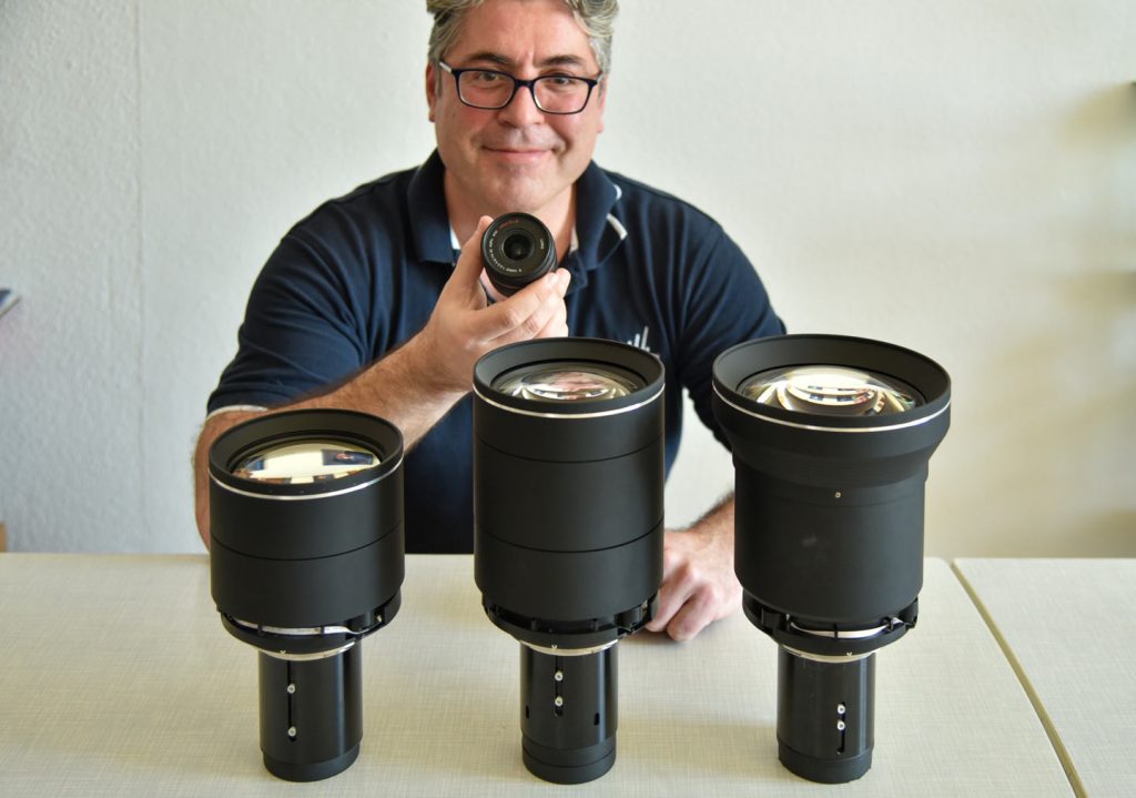 Größenvergleich: Chris hält ein Panasonic (Leica) Foto-Zoom. Auf dem Tisch die drei Standard-Zooms für den Bragi: Tele, Normal und Superweitwinkel (Foto: R. Vogt)